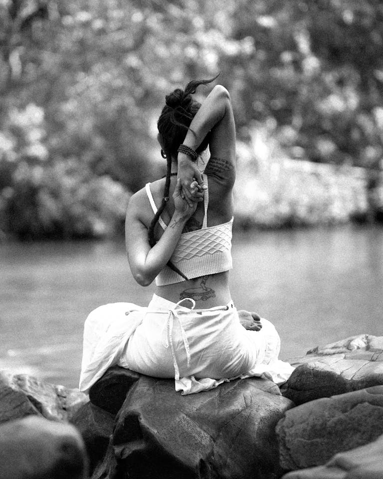 A woman practicing yoga near a river in a serene outdoor setting, embodying tranquility and focus.