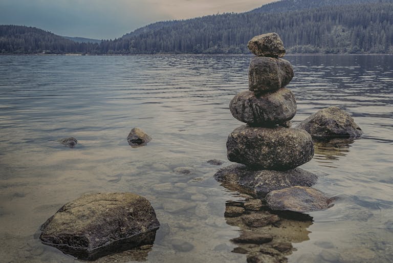 Peaceful lake scene at Schluchsee, Germany, showcasing rock balancing and scenic nature.